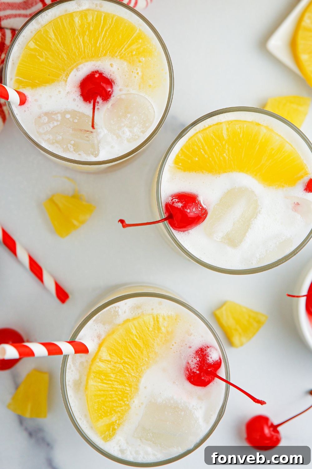 Island Escape Punch 14 Multiple glasses of Piña Colada Punch on a table, each garnished with pineapple and cherries.