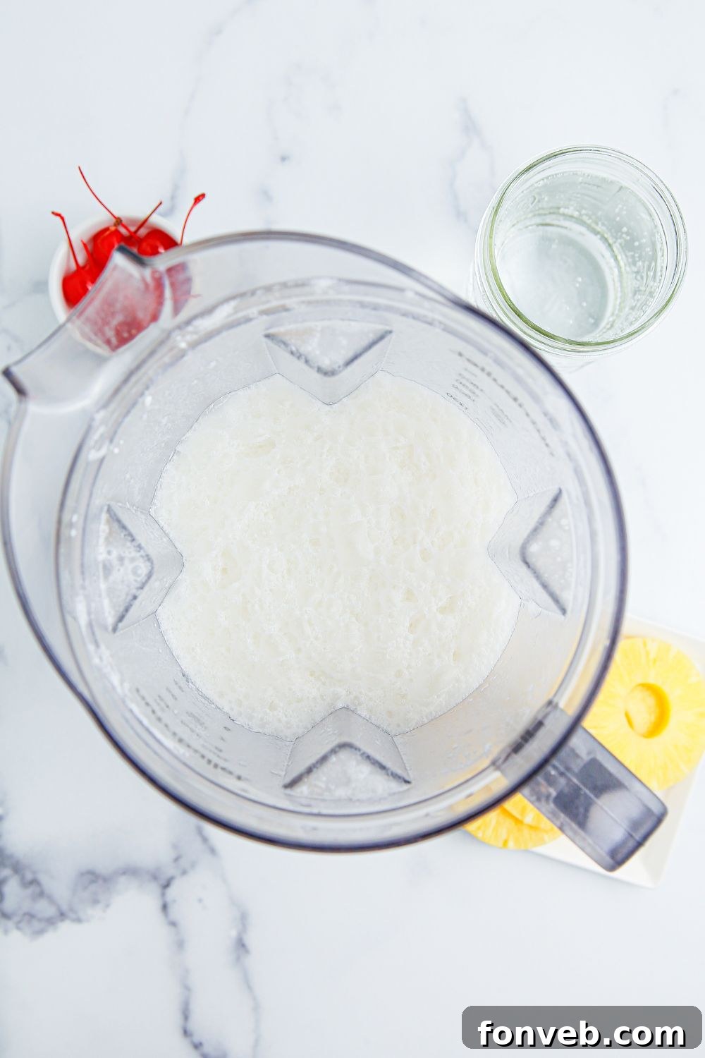 Island Escape Punch 6 Blender filled with pineapple juice and cream of coconut, ready to be blended for the punch.