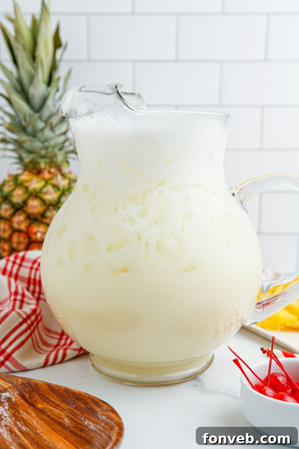 Island Escape Punch 7 Freshly mixed Piña Colada Punch in a clear glass pitcher, showing its creamy, light yellow color.