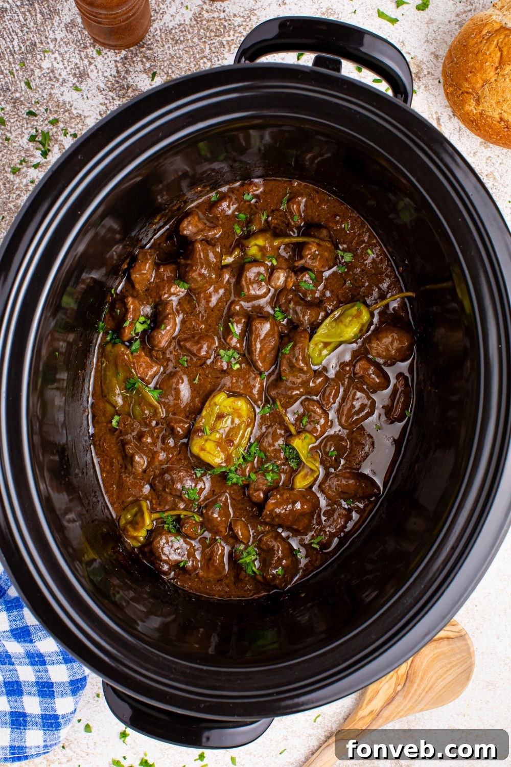 Tender Mississippi Crockpot Steak Bites 11 Overhead view of cooked Mississippi Steak Bites in a slow cooker, garnished with parsley.