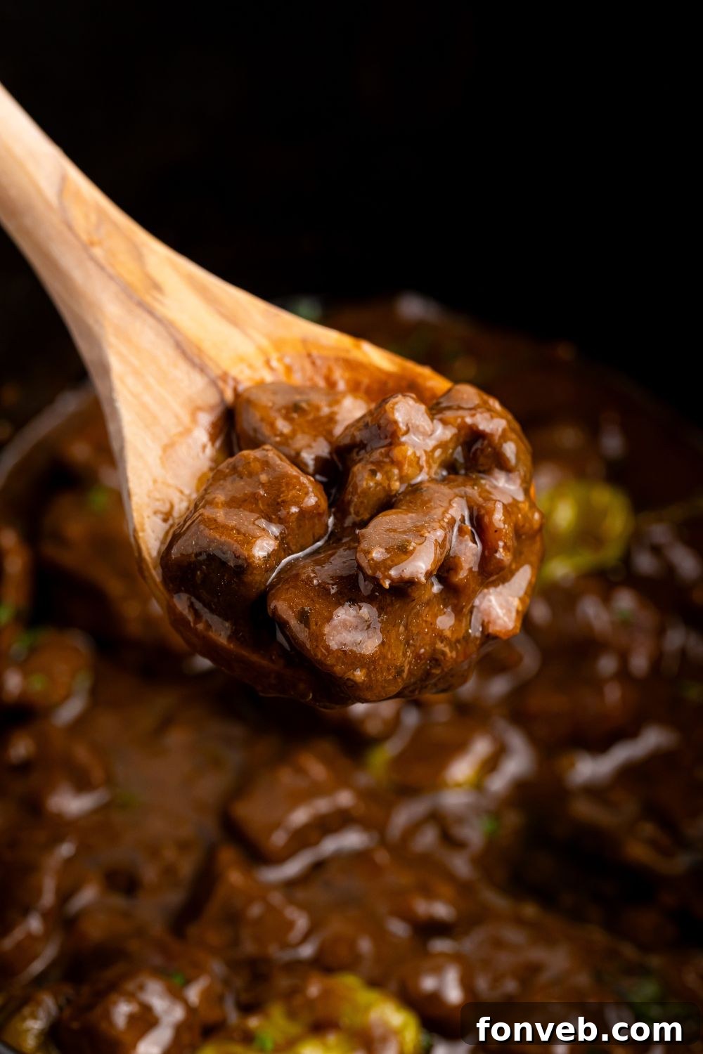 Tender Mississippi Crockpot Steak Bites 12 Cooked Mississippi Steak Bites being stirred with a wooden spoon in the slow cooker.