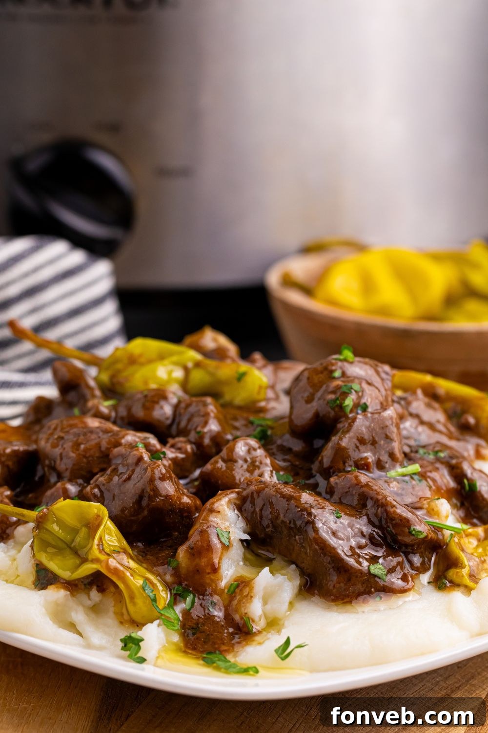 Tender Mississippi Crockpot Steak Bites 14 A plate of Mississippi Steak Bites, with the slow cooker visible in the background, ready for serving.