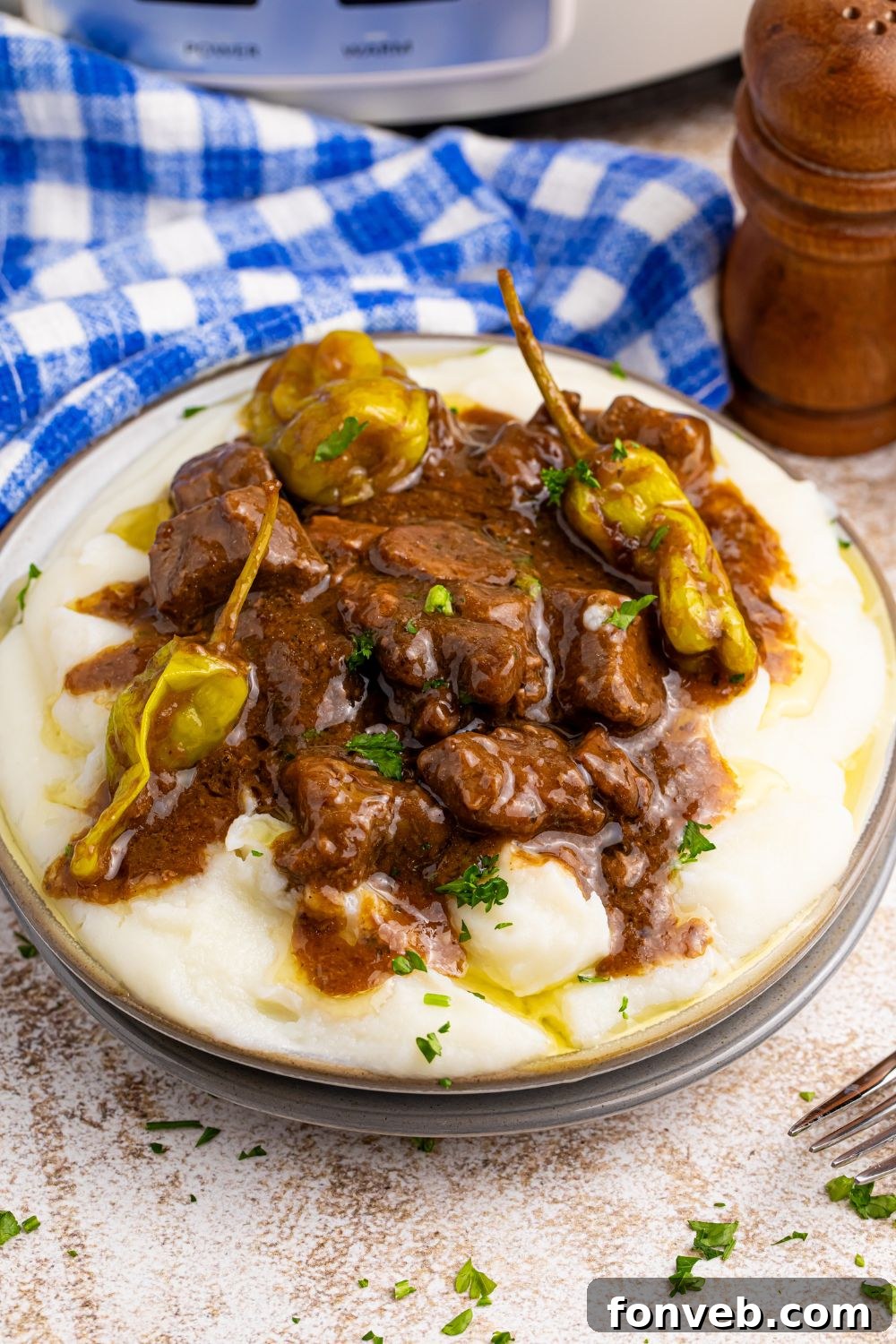 Tender Mississippi Crockpot Steak Bites 16 A rustic square plate of Mississippi Steak Bites, with a blue checkered towel adding a touch of homey charm.
