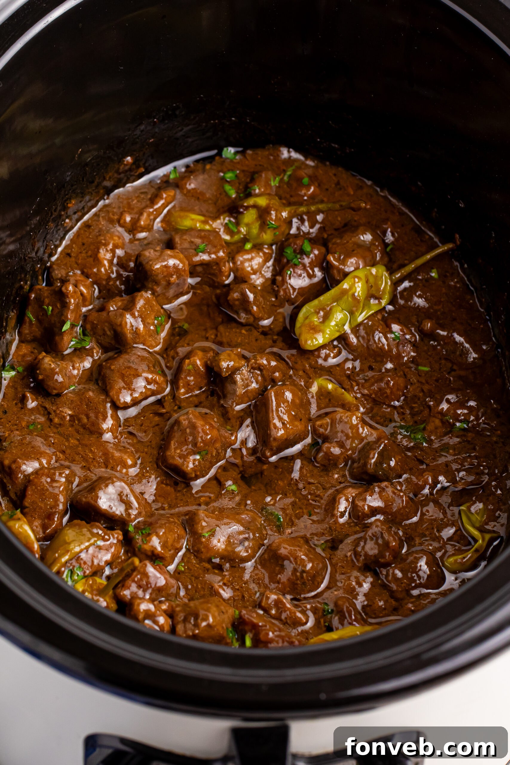 Tender Mississippi Crockpot Steak Bites 19 Overhead shot of Mississippi Steak Bites simmering in a slow cooker, garnished with fresh parsley.