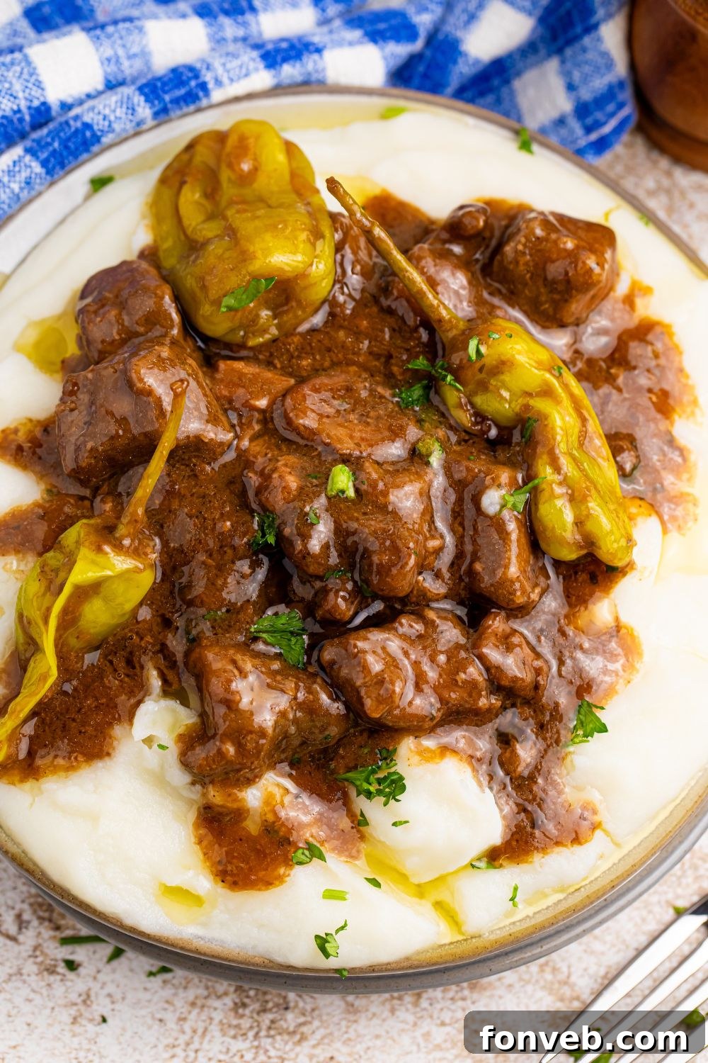 Tender Mississippi Crockpot Steak Bites 21 A vibrant plate of Mississippi Steak Bites with mashed potatoes, garnished with peppers and fresh herbs.