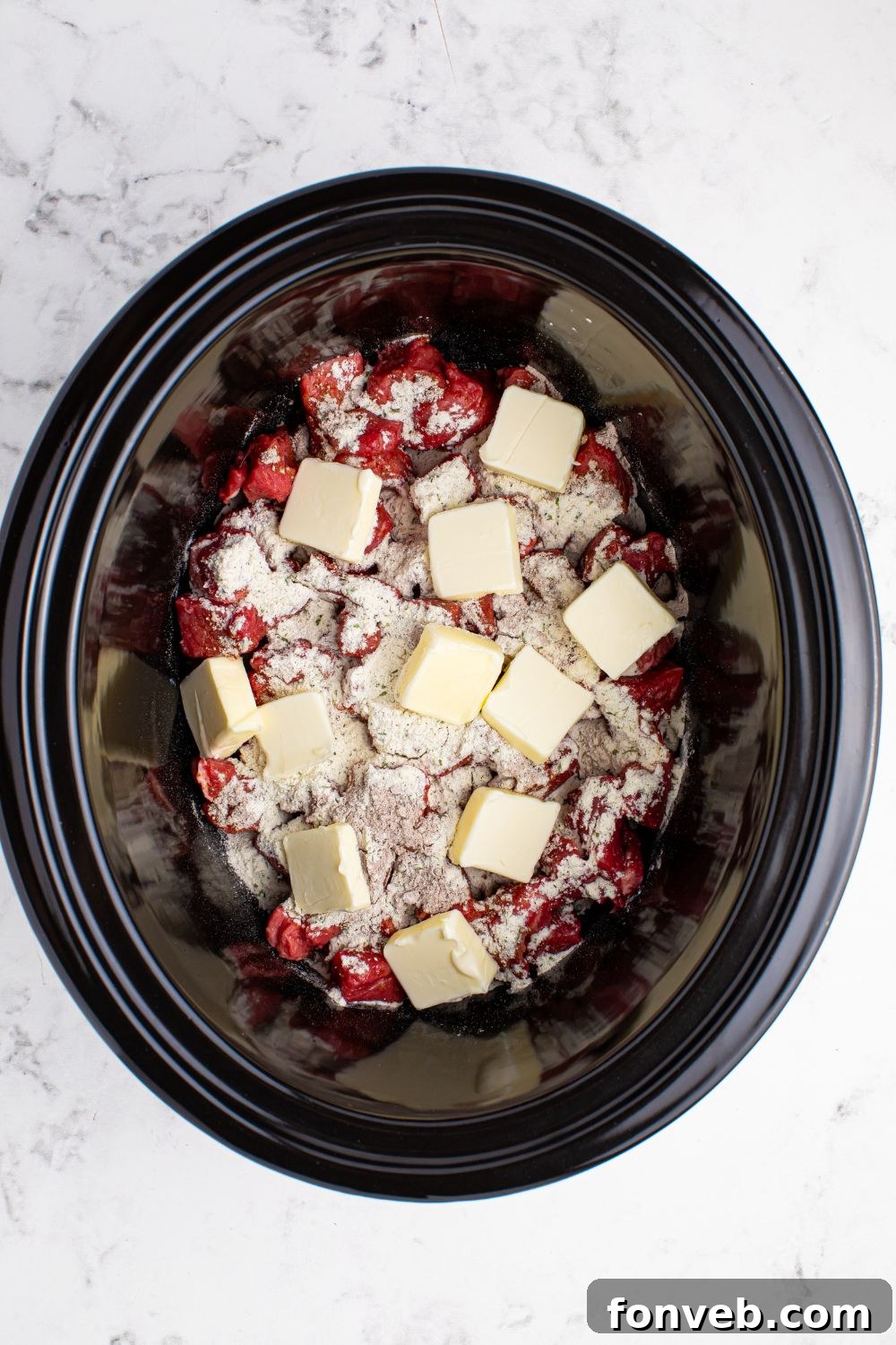 Tender Mississippi Crockpot Steak Bites 10 Steak in the slow cooker with seasonings, butter pats, and peppers added.