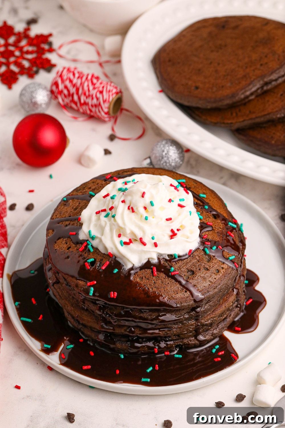 Decadent Hot Chocolate Pancakes 12 Hot Chocolate Pancakes with whipped cream on plate with christmas decor behind it