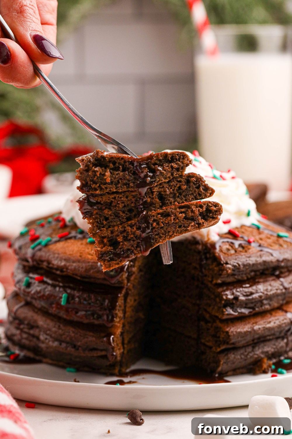 Decadent Hot Chocolate Pancakes 18 fork with some pancakes on it and plate of Hot Chocolate Pancakes in the background