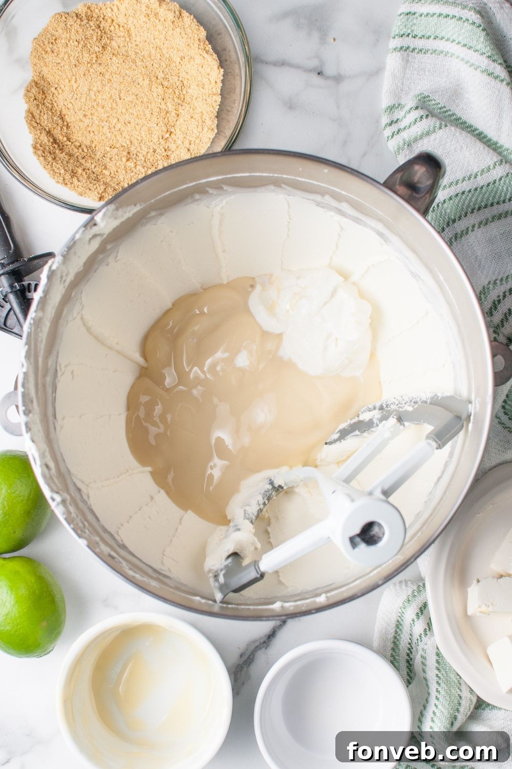 Tangy Key Lime Pie Cookies 11 Crumbl Key Lime Pie Cookie filling in a mixer bowl with condensed milk poured in the center of bowl