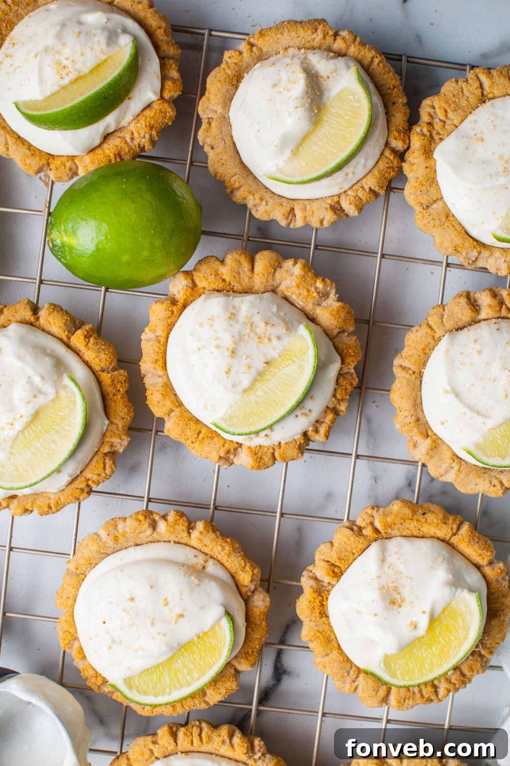 Tangy Key Lime Pie Cookies 15 Crumbl Key Lime Pie Cookies on a cooling rack garnished with lime wedge and graham crackers
