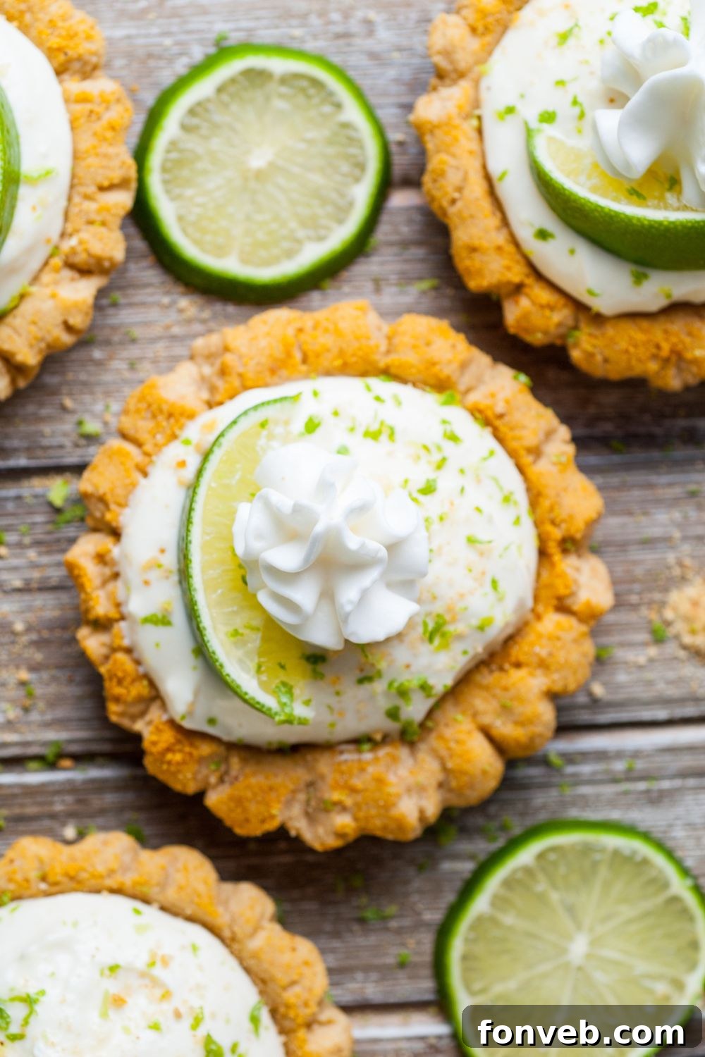 Tangy Key Lime Pie Cookies 4 Crumbl Key Lime Pie Cookies spread out on a wooden table with lime slices around the cookies