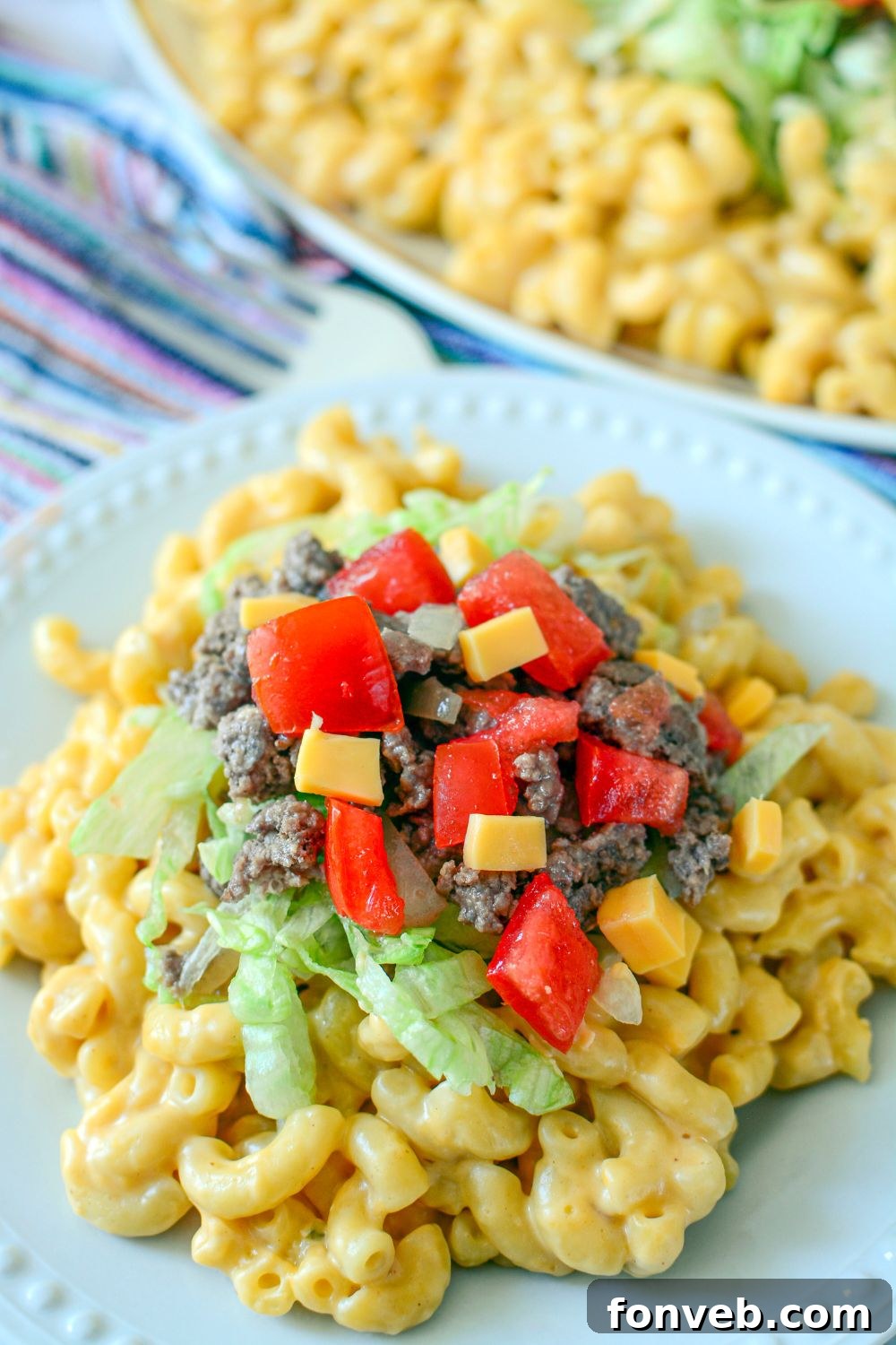 Big Mac Macaroni And Cheese on a plate with some toppings of tomatoes, cheese, beef and lettuce 