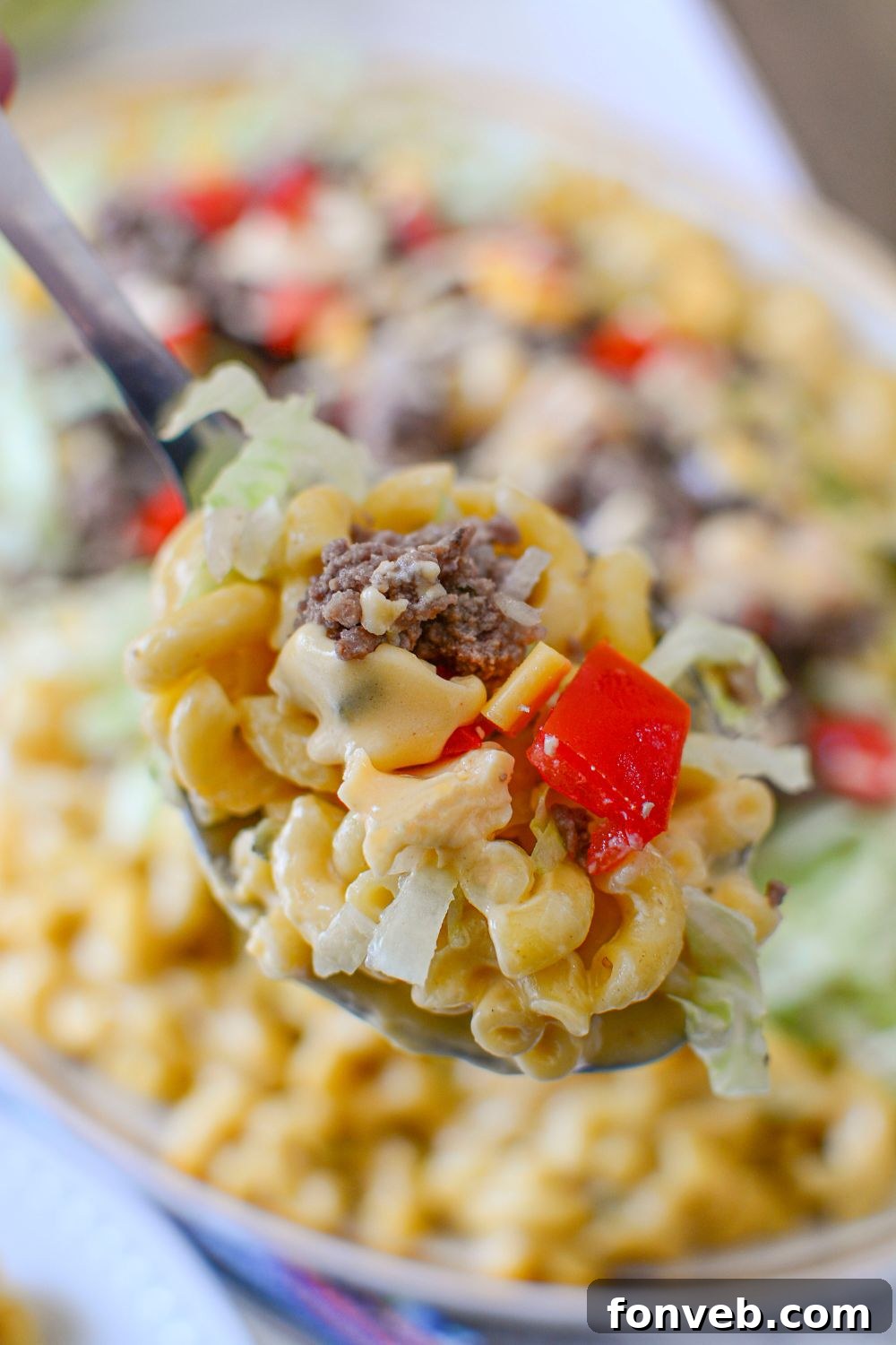 Big Mac Macaroni And Cheese in a spoon above the platter 