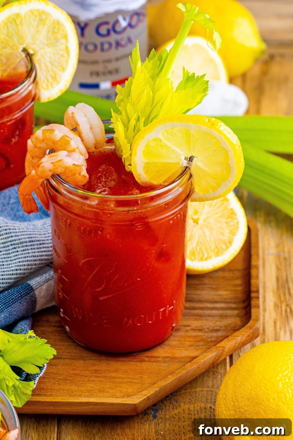 Bloody Mary on cutting board with celery and lemons sitting around the glasses 