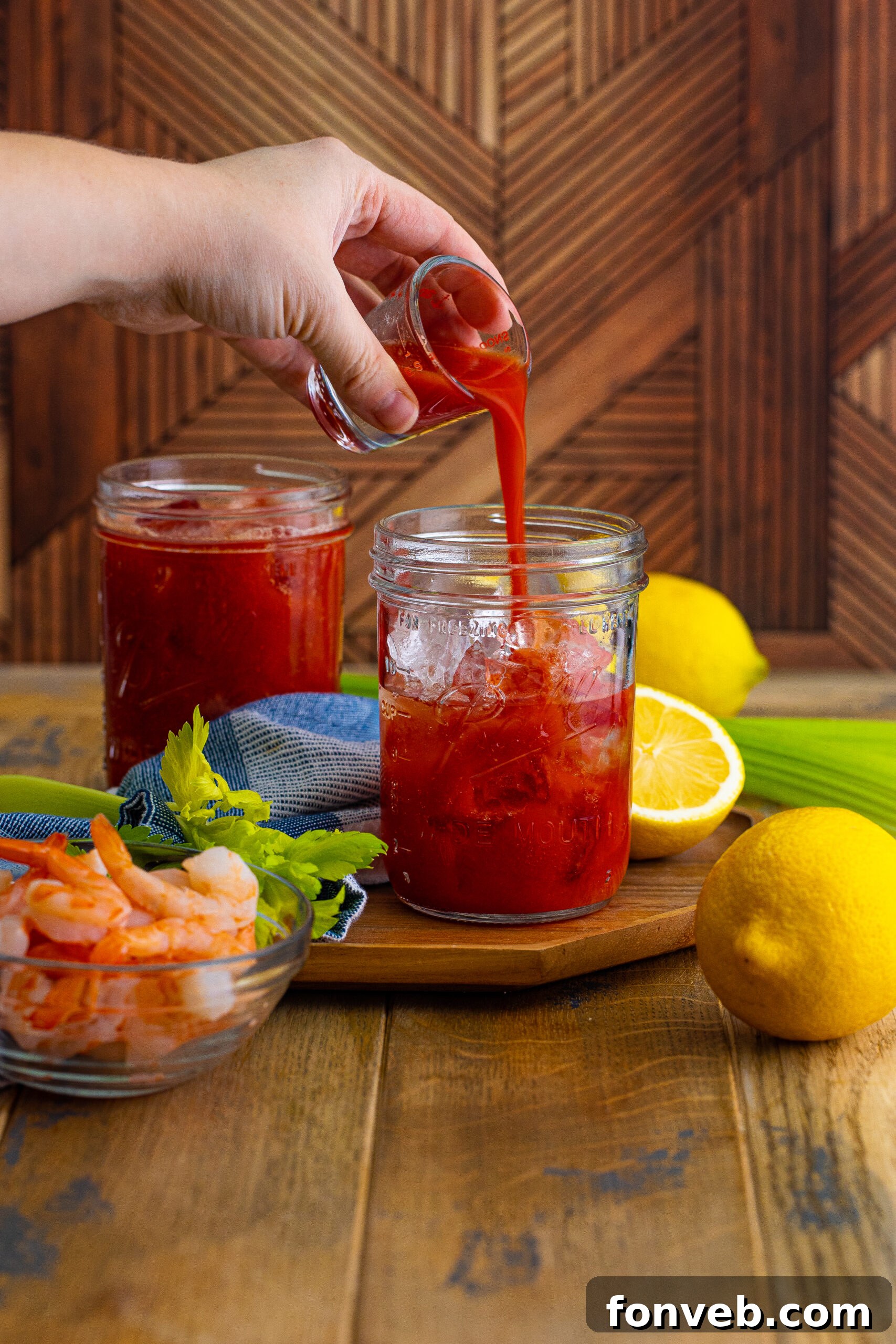 Bloody Mary on table with tomato juice pouring into glasses 