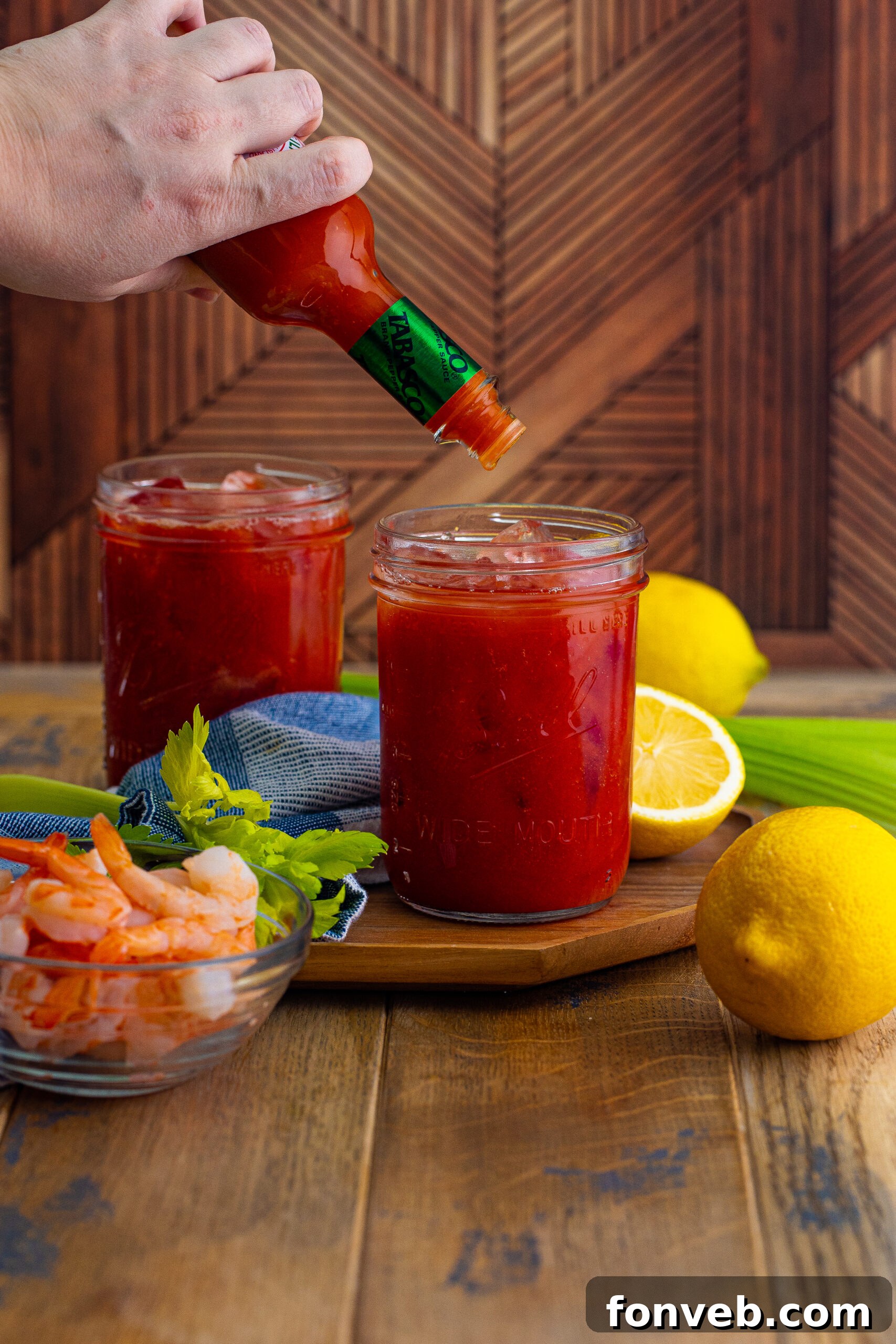 Bloody Mary with hot sauce being poured into glass 