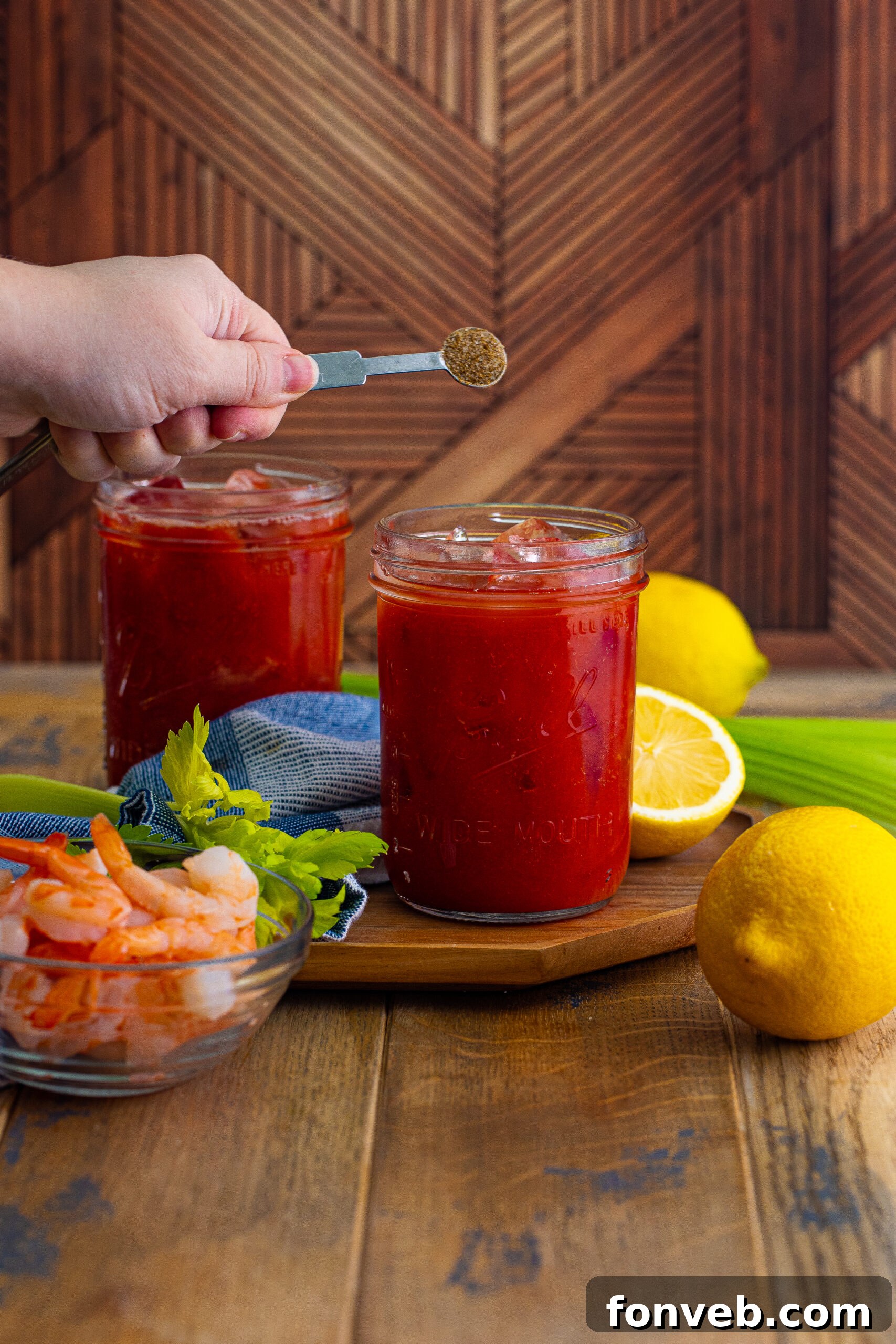 Bloody Mary on table with measuring spoon being poured into glass 