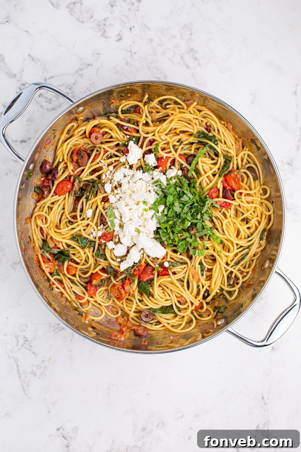 Greek Spaghetti ingredients in a pan with feta and basil on top