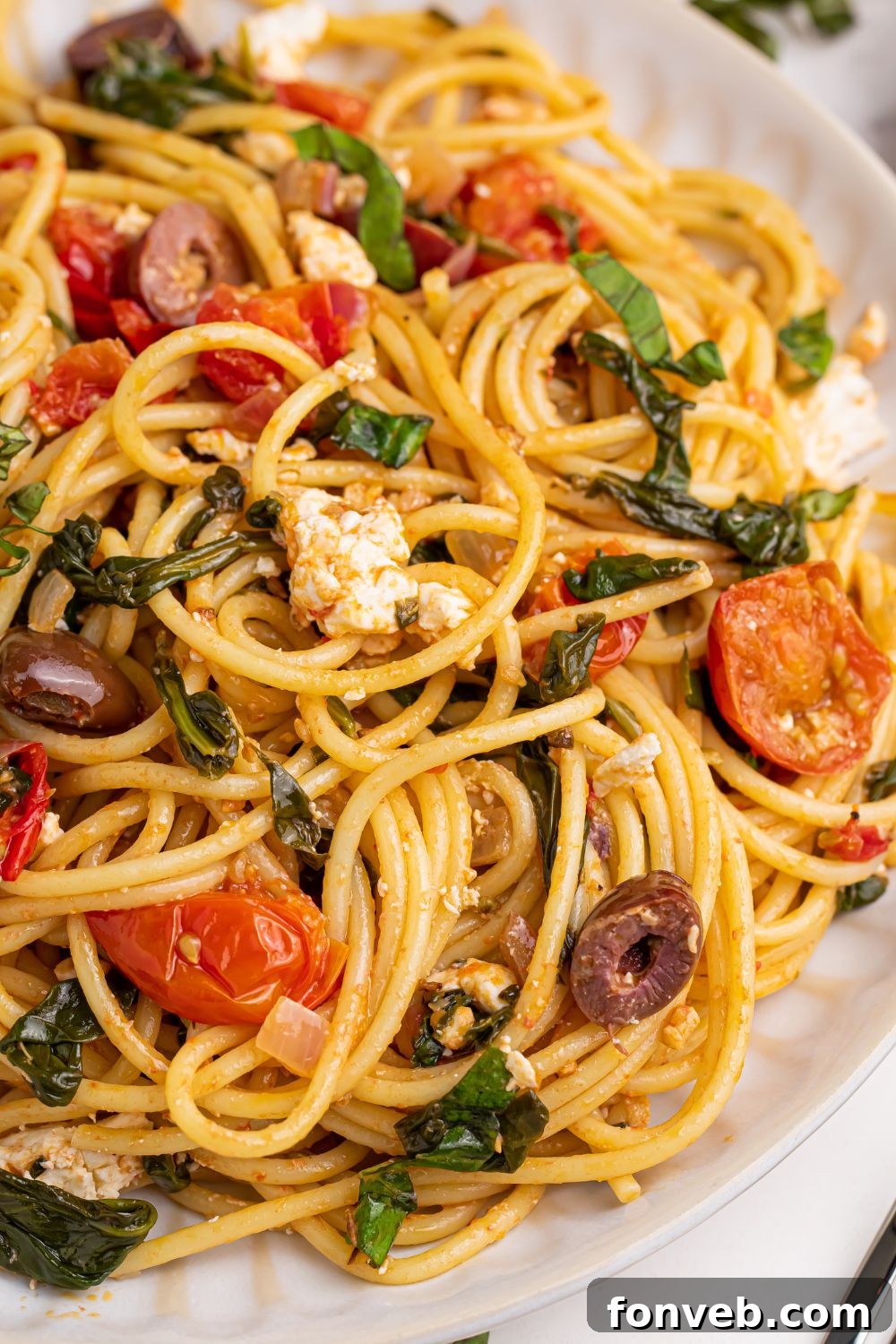 Greek Spaghetti on a plate with a side view to showcase all the ingredients in the dish, emphasizing its richness.