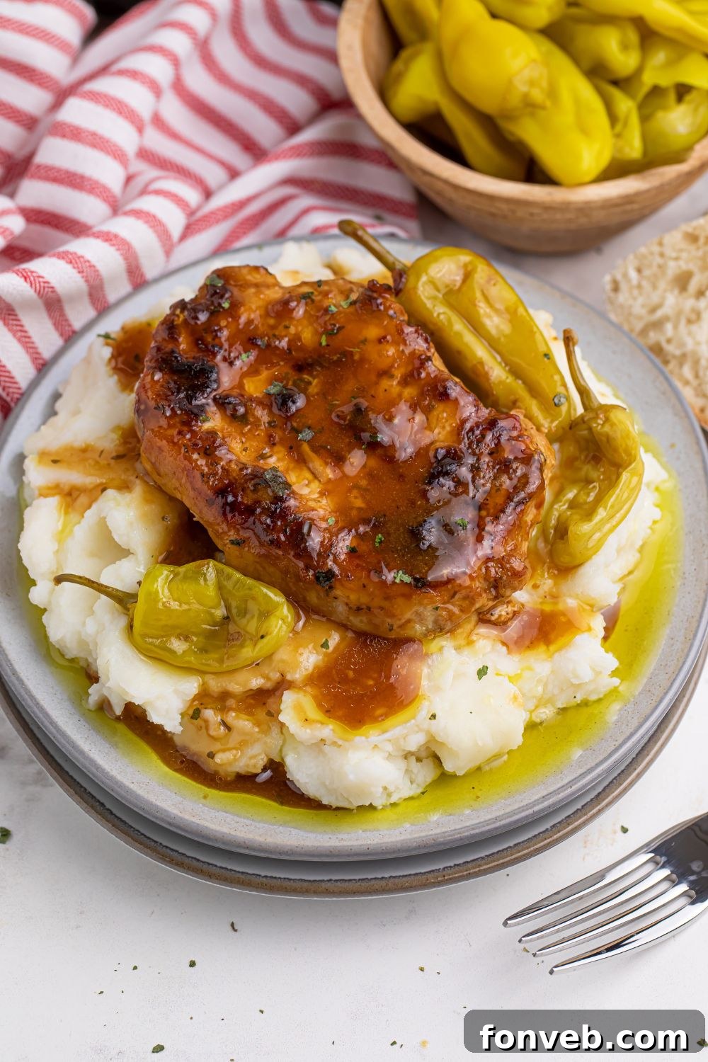 Crock Pot Mississippi Pork Chops on a plate with pork chop, mashed potatoes, and peppers 
