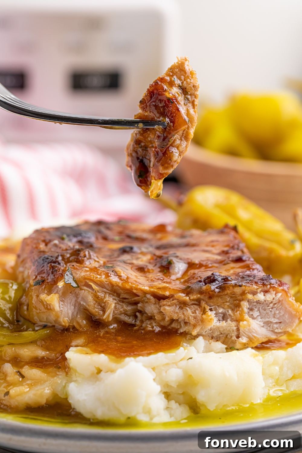 Crock Pot Mississippi Pork Chops on plate with a fork with a bite of pork chop on it 