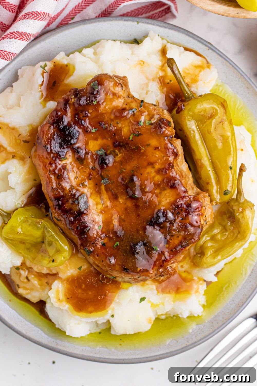 Crock Pot Mississippi Pork Chops overhead shot on a plate with peppers and ptatoes under the pork chops 