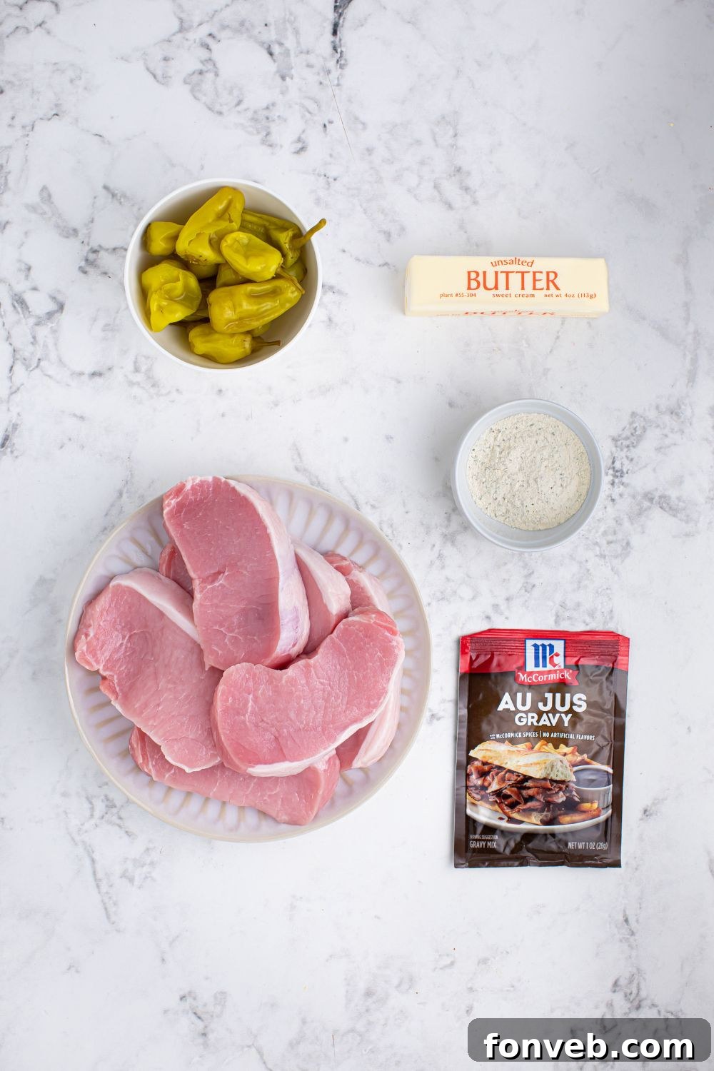 Crock Pot Mississippi Pork Chops ingredients on table - pork chops, au jus packet, ranch seasoning, stick of butter, peppers 