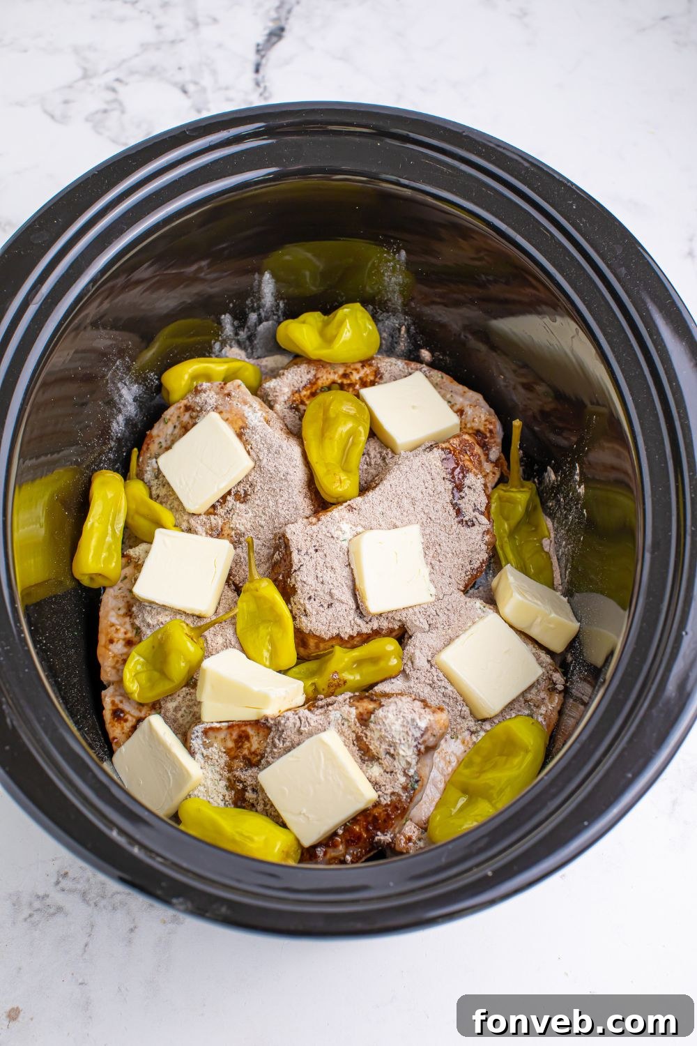 Crock Pot Mississippi Pork Chops ingredients in a slow cooker with slabs of butter on top 