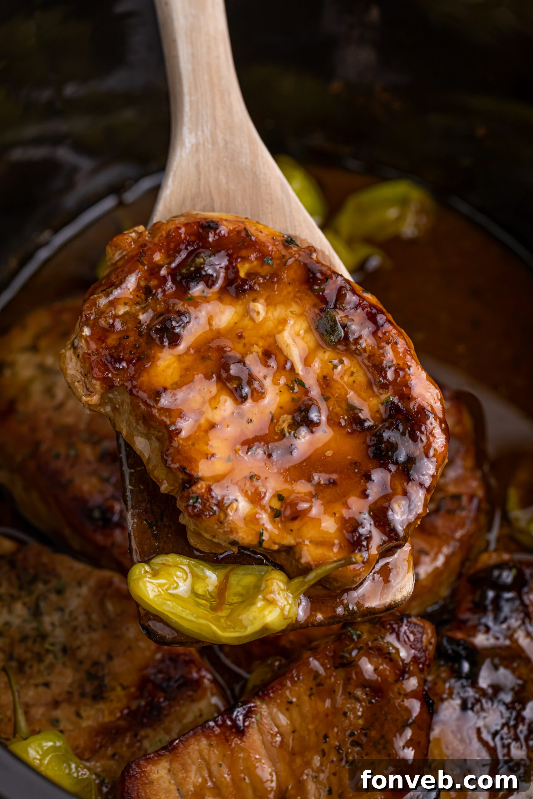 wooden spoon lifting a pork chop and pepper