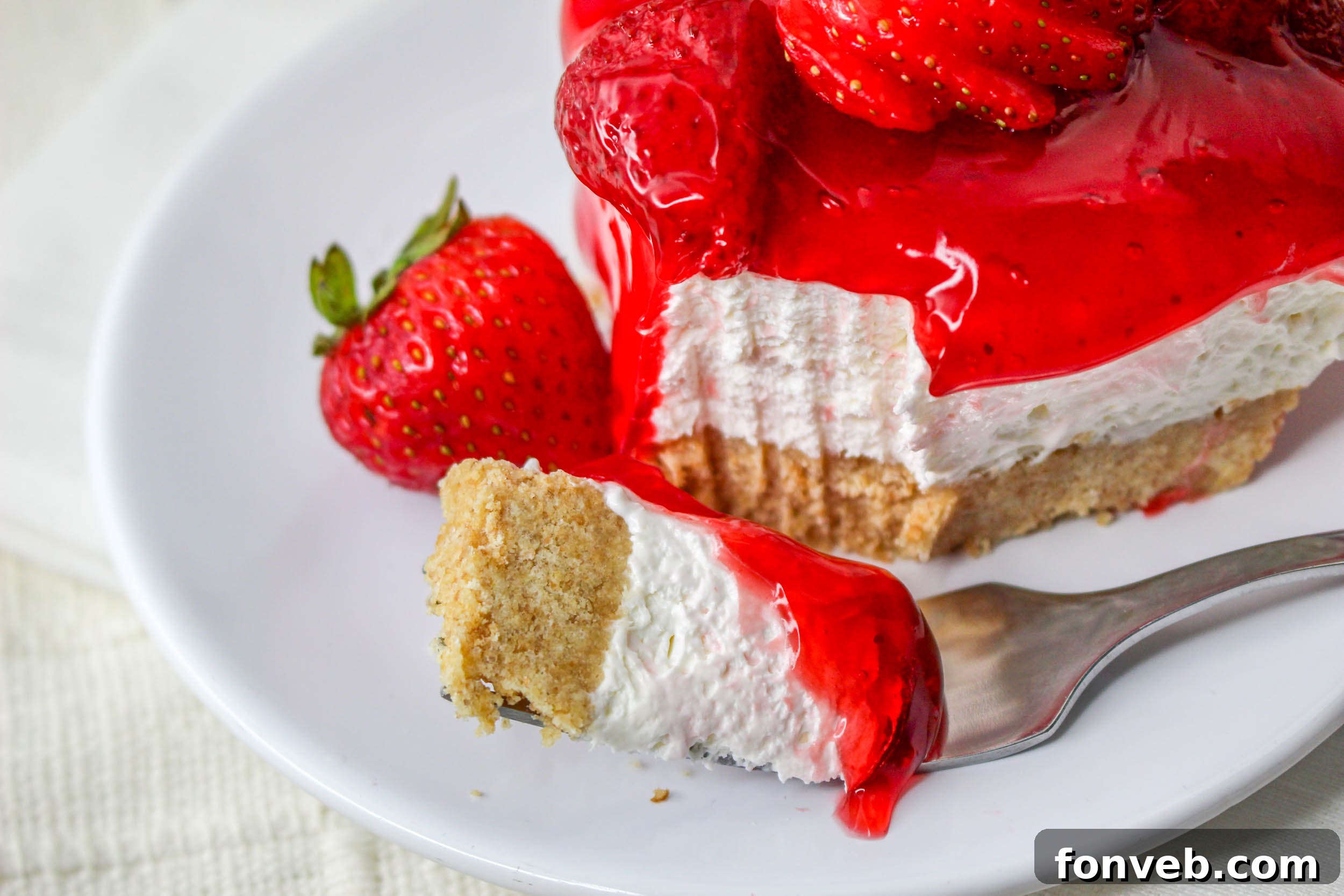 No Bake Strawberry Delight on a white plate with a bite missing topped with sliced strawberries 