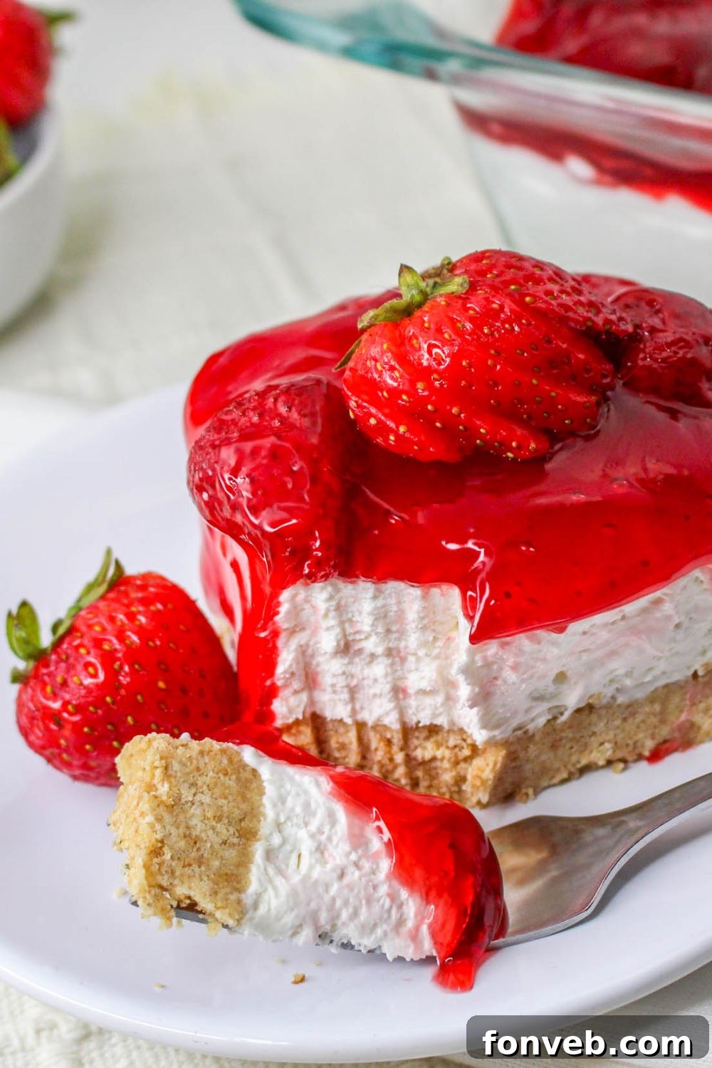 No Bake Strawberry Delight on plate with a fork with a bite on it and berry on plate 