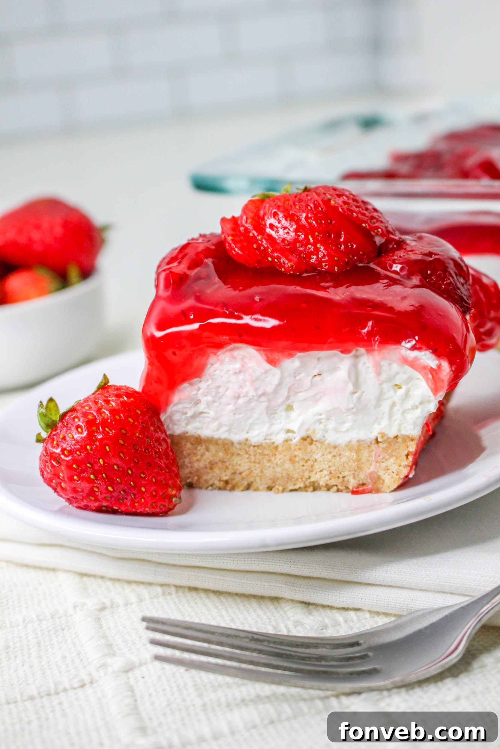 Further away view of the No Bake Strawberry Delight on a white plate topped with sliced strawberries 