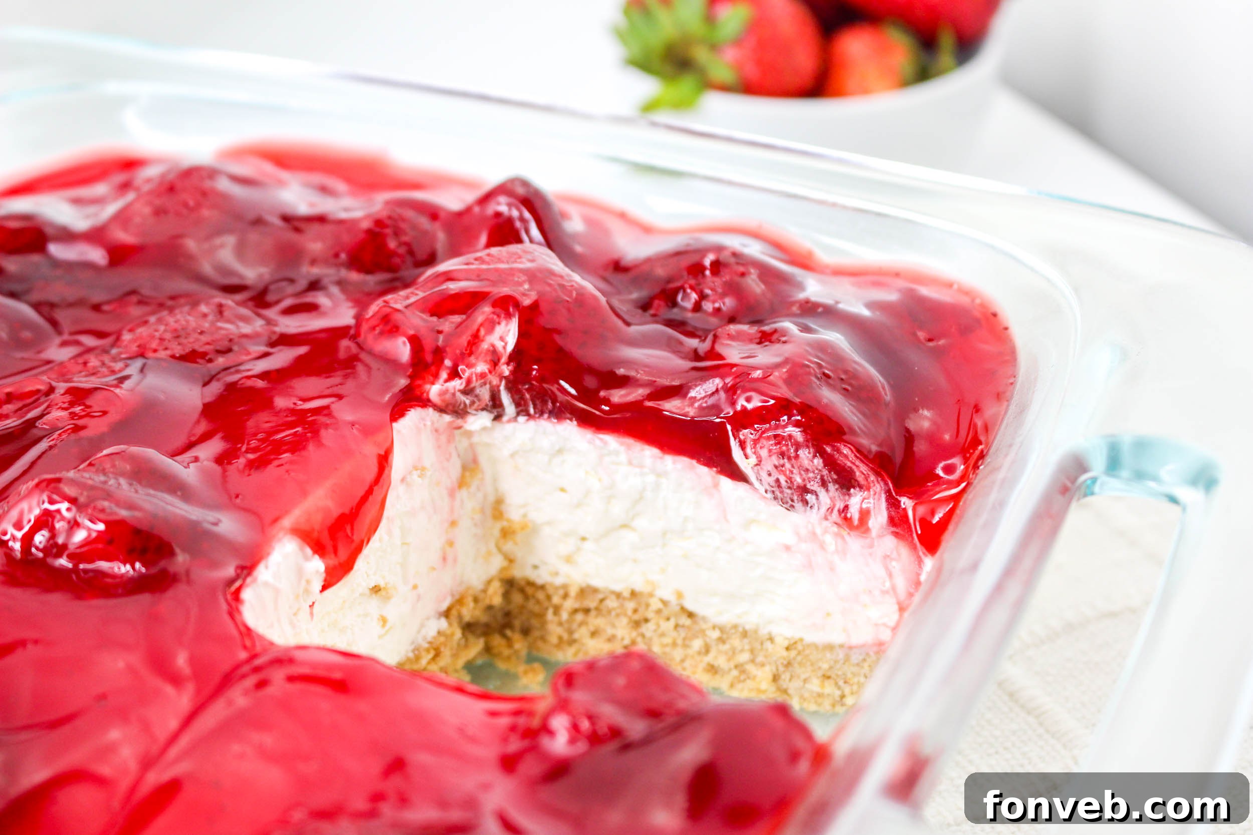 No Bake Strawberry Delight in a clear baking pan with a slice removed