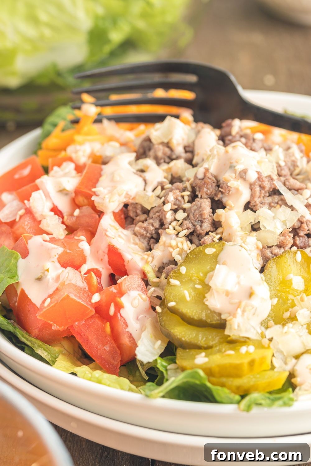 Big Mac Makeover Salad 13 Big Mac Salad neatly presented in a bowl with a black fork resting alongside, ready to be enjoyed.