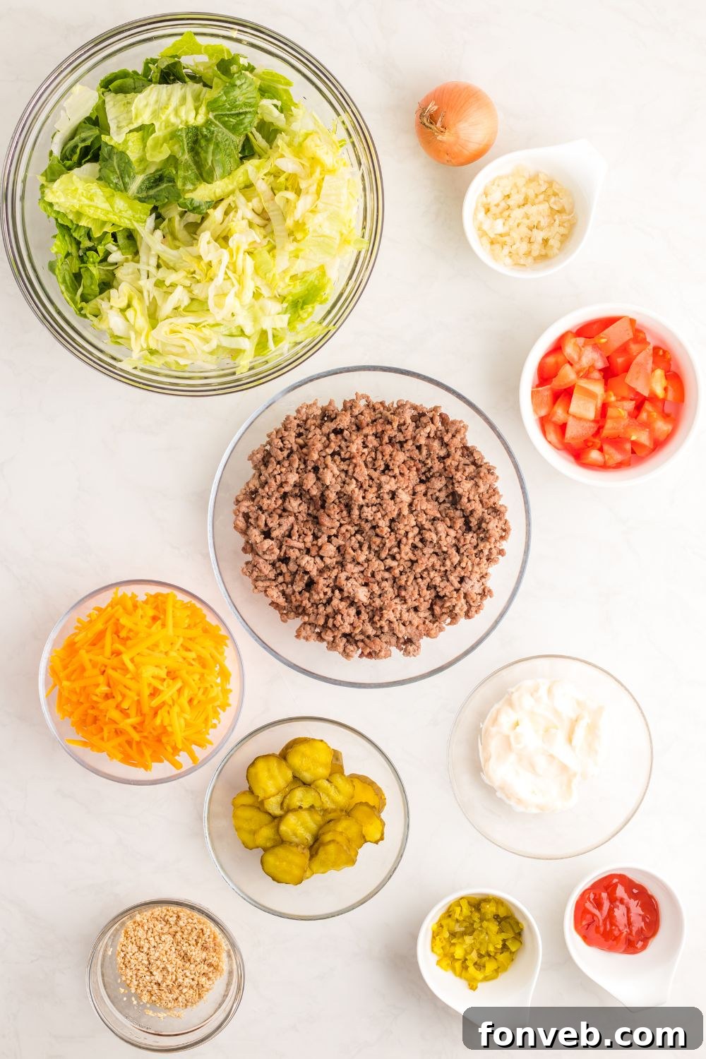 Big Mac Makeover Salad 5 Assorted Big Mac Salad ingredients laid out in small bowls on a clean white table, ready for assembly.