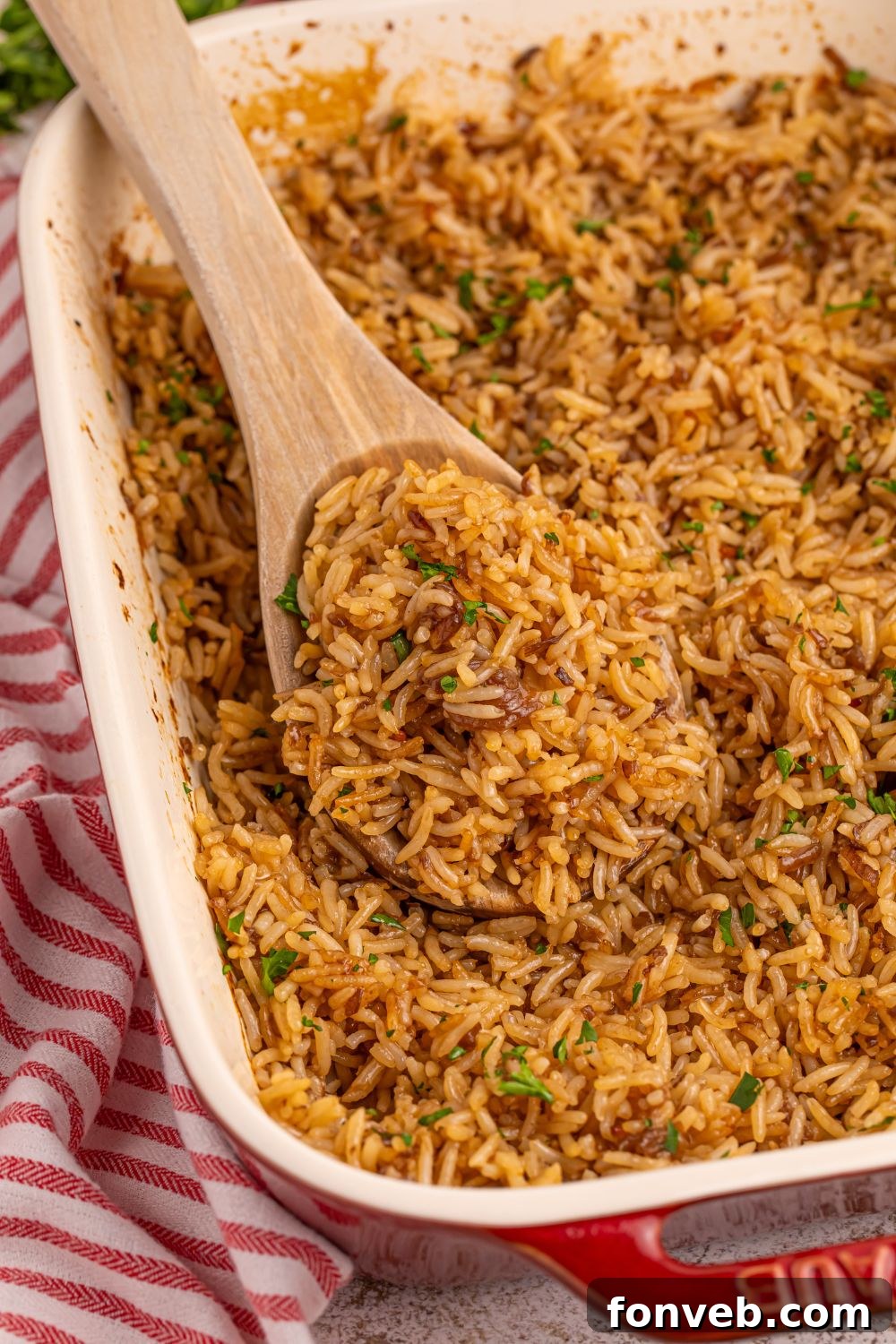 Stick of Butter Rice in a pan with a wooden spoon with some rice on it sitting in pan 