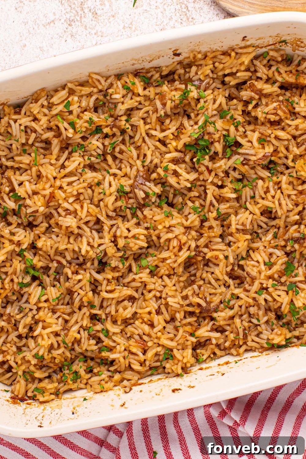 Stick of Butter Rice baked in a casserole pan on table with a red towel under it 