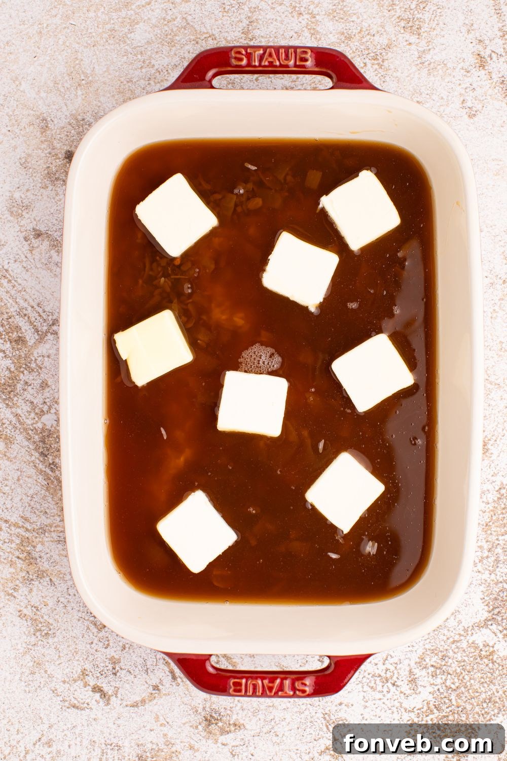 Stick of Butter Rice mixture in a casserole dish with slabs of butter on top
