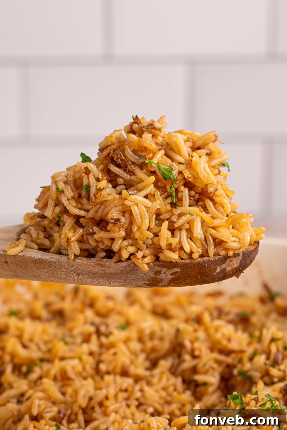 Stick of Butter Rice on a wooden spoon above pan