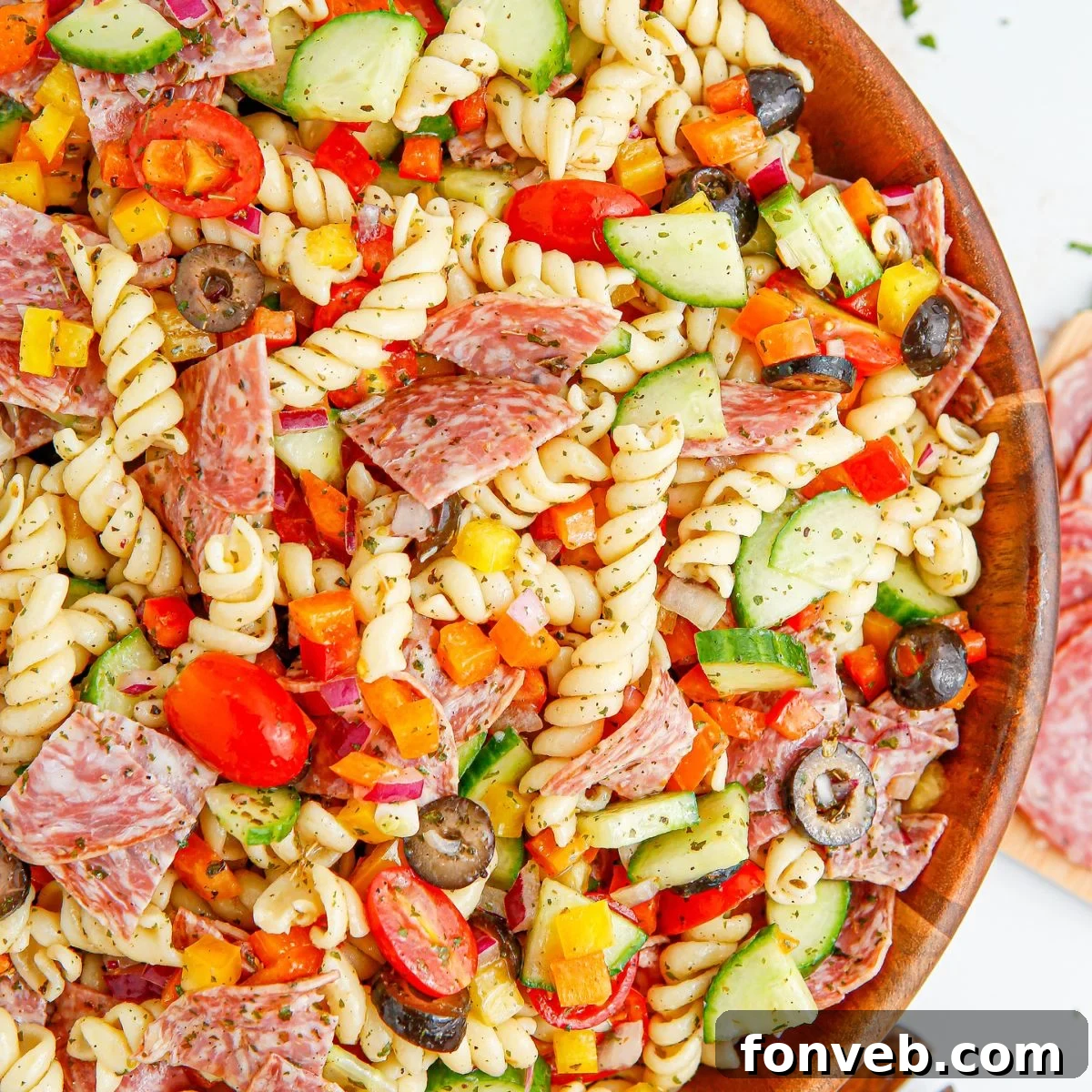 Summer Pasta Salad in a wooden bowl on table, garnished with fresh herbs.