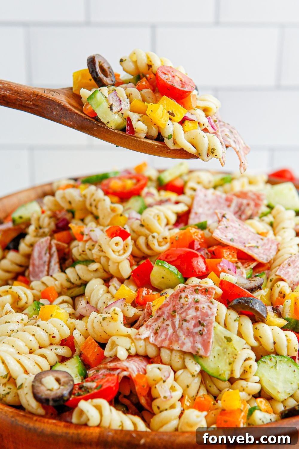 Summer Pasta Salad served in a rustic wooden bowl with a spoonful ready to be enjoyed.