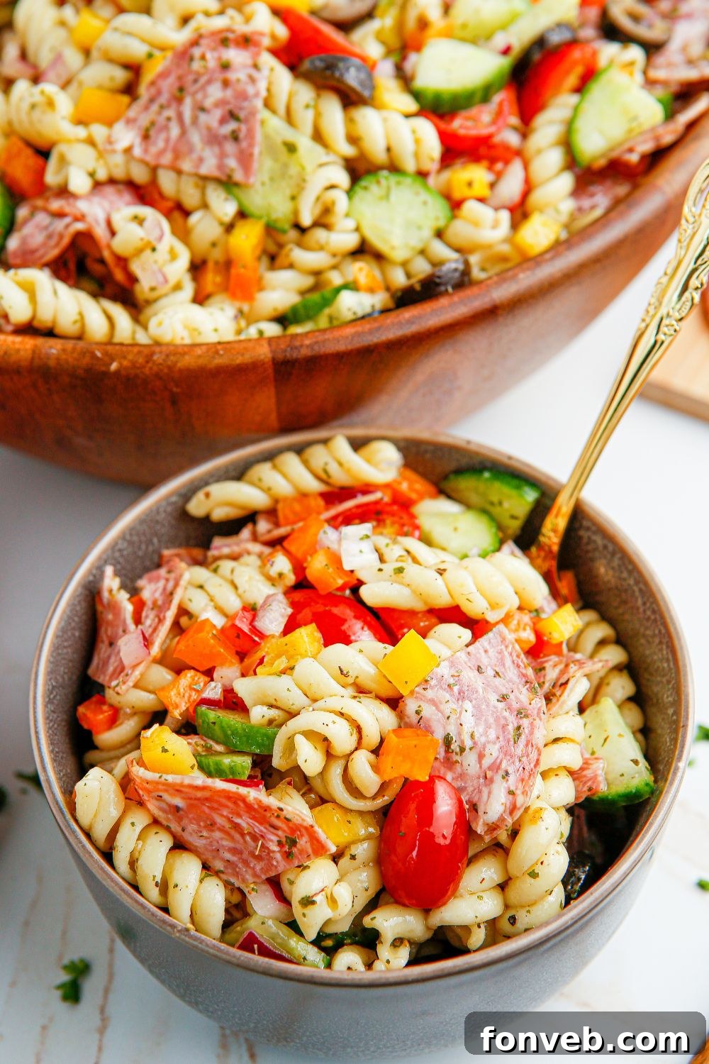 Summer Pasta Salad served in a small white bowl with a spoon, showing the rich colors of the ingredients.