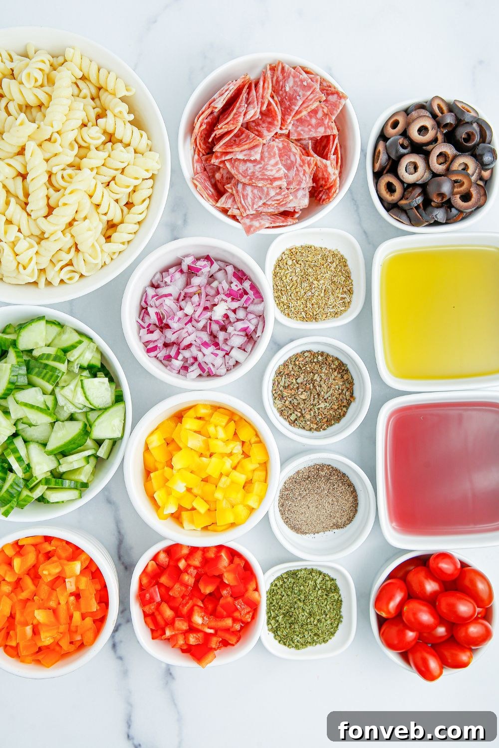 Individual ingredients for Summer Pasta Salad arranged in small white bowls on a rustic wooden table.