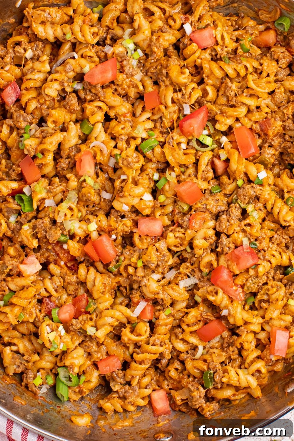 A close-up of the rich, bubbling surface of Taco Macaroni and Cheese in a pan, showcasing the melted cheese and seasoning.