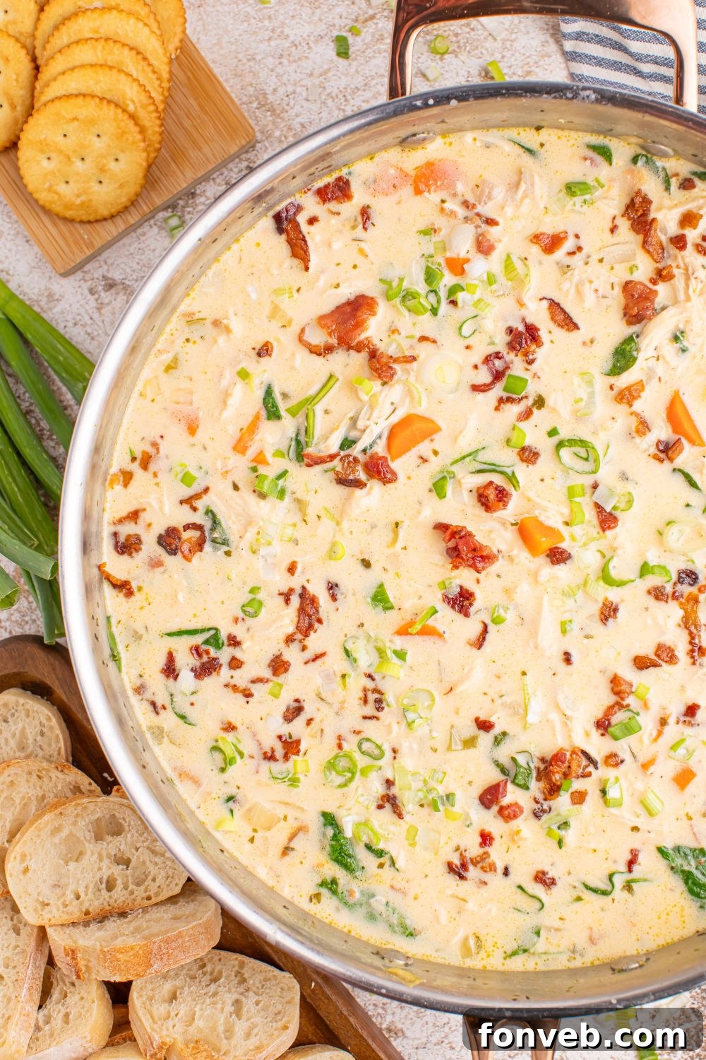 A large pan of delicious Crack Chicken Soup, accompanied by crispy crackers and slices of fresh bread