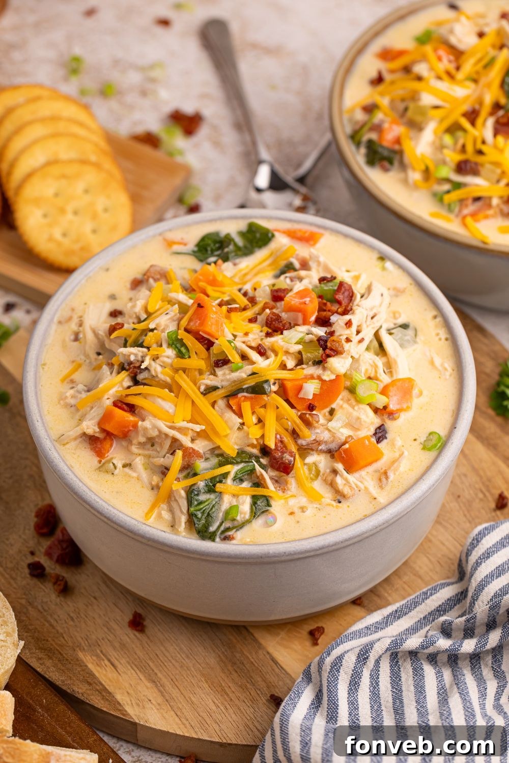 Two cozy bowls of Crack Chicken Soup ready for serving, with spoons and crackers in the background