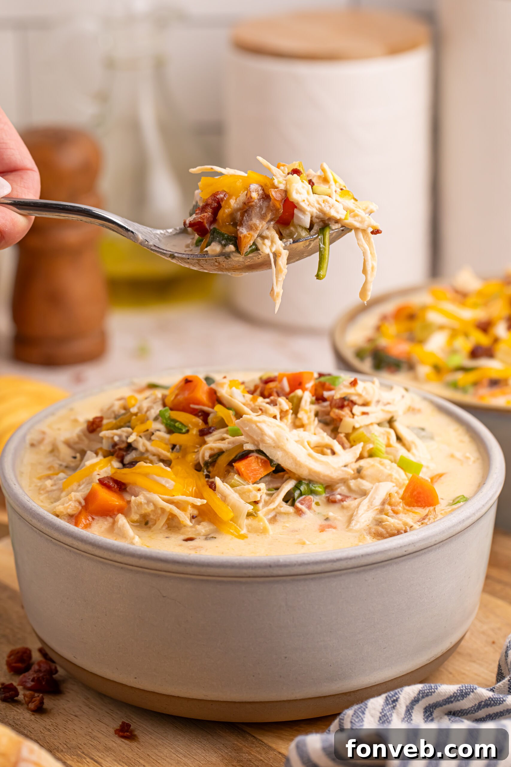 A spoon lifting a generous bite of creamy Crack Chicken Soup from a white bowl, showing its appetizing texture