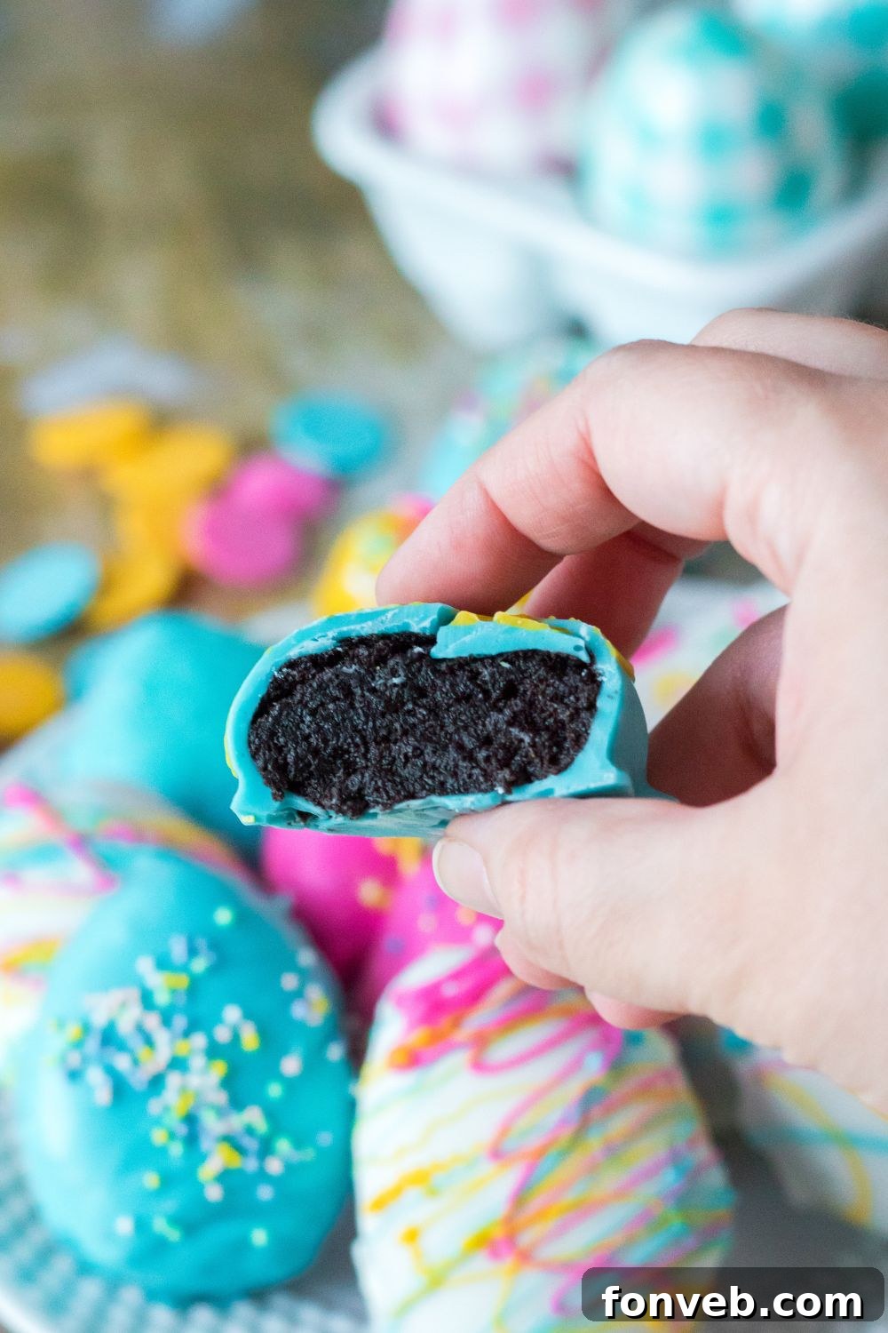 Festive Easter Egg Oreo Truffles 11 A perfectly dipped Easter Egg Oreo Truffle held in hand, showing a clean bite revealing the creamy Oreo filling inside, highlighting its delightful texture and taste.
