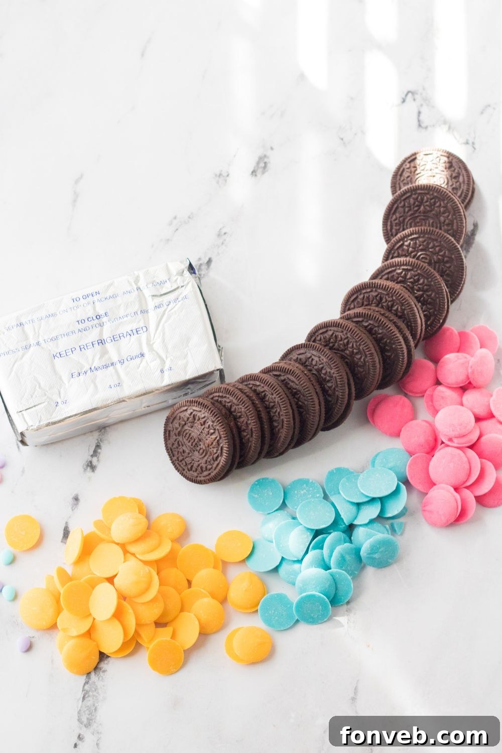 Festive Easter Egg Oreo Truffles 5 All the essential ingredients for making Easter Egg Oreo Truffles neatly laid out on a clean marble countertop, including cream cheese, Oreo cookies, white almond bark, colored candy melts, and a variety of Easter sprinkles.