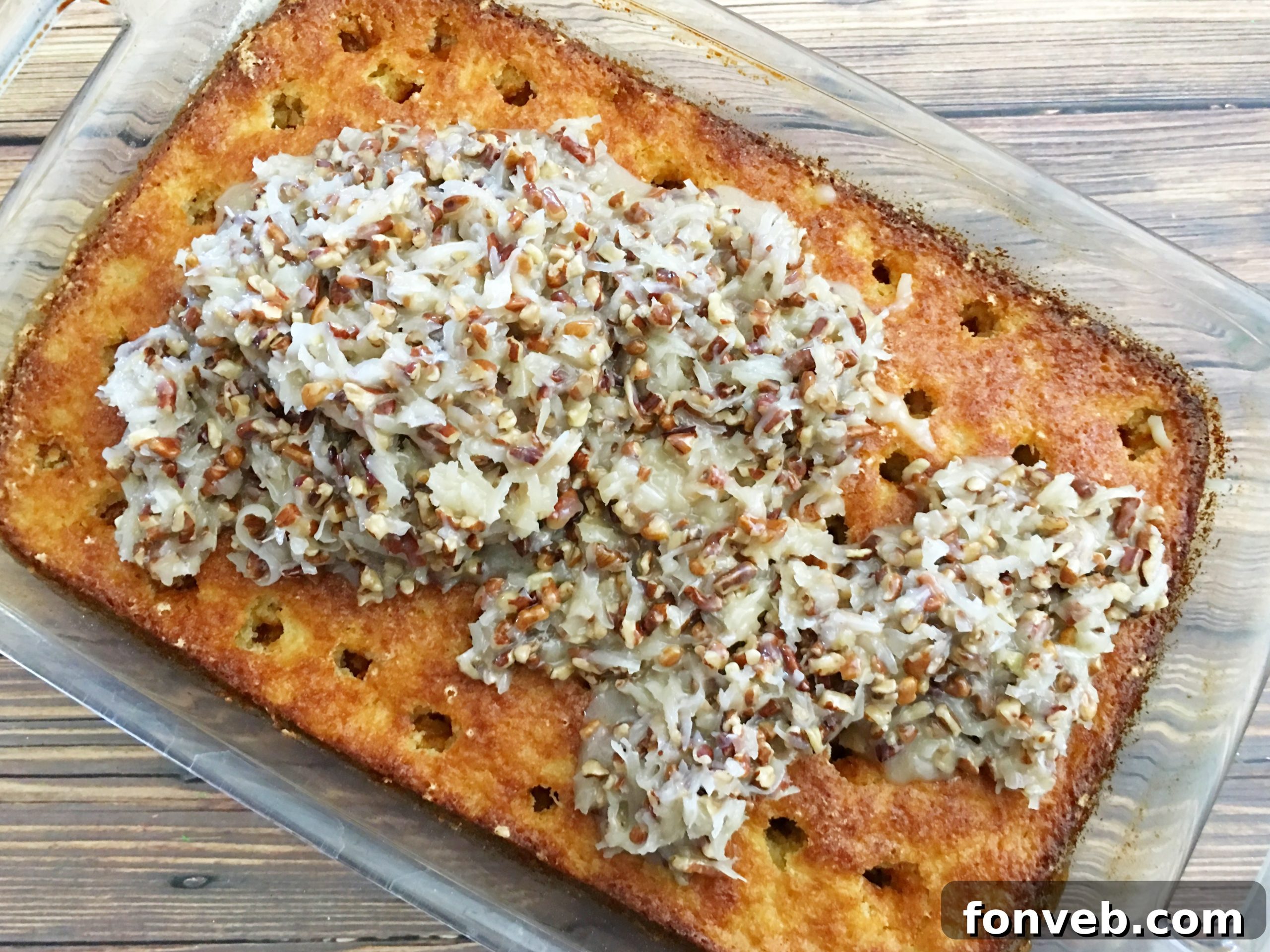 Poking holes in the baked cake with a wooden spoon handle, preparing for the topping.
